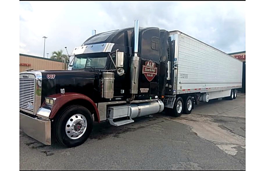 Black Freightliner semi number 007 hooked to a white trailer